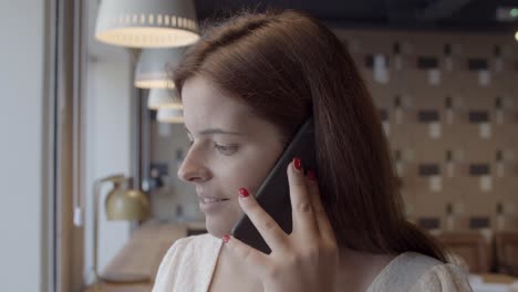 mujer joven pensativa positiva hablando por teléfono celular