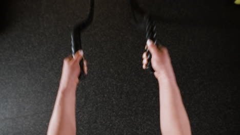 Woman performing rope pull-ups in a gym