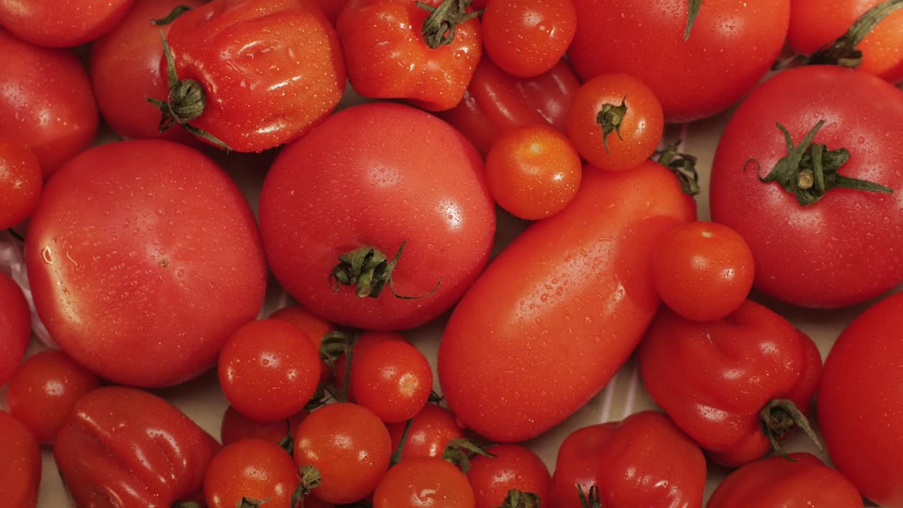 Colorful organic tomatoes. Mix tomatoes background, Several varieties of sliced tomatoes top view. Different assorted colorful tomatoes, heirloom, cherry, rose, beefsteak, cocktail, grape, purple.