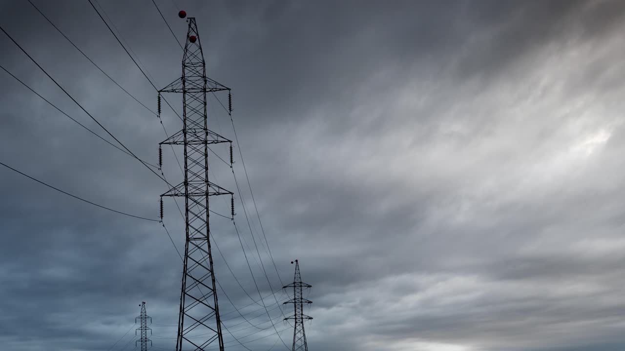 electricity pylon against storm clouds time-lapse, electrical transmission tower and high voltage power lines with dark clouds
