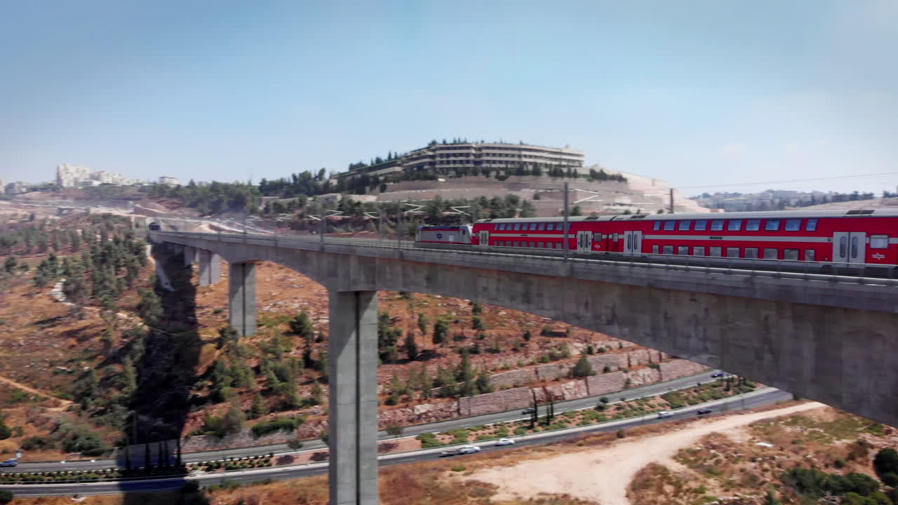 Modern passenger train crossing a bridge in the outskirts of Jerusalem, Aerial footage