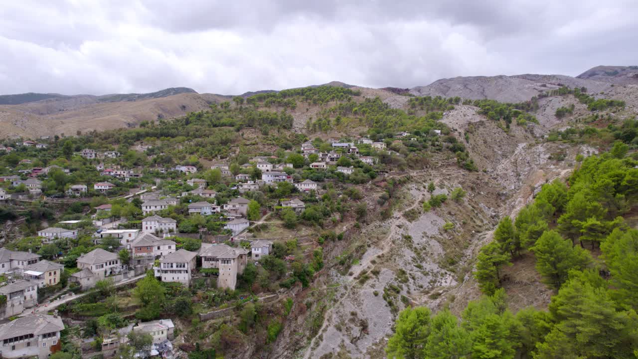 Hava çekimlerinde, kapalı bir günde dik kayalık bir uçurumun yanındaki yeşil tepelere dağılmış küçük bir köy ve pürüzsüz kaydırma kamera hareketi görülüyor