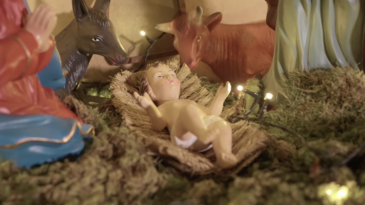 nativity scene with baby jesus in straw lit by soft festive lights