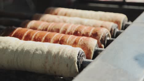 changing one of the baking hungarian chimney cakes from others above the glowing ember