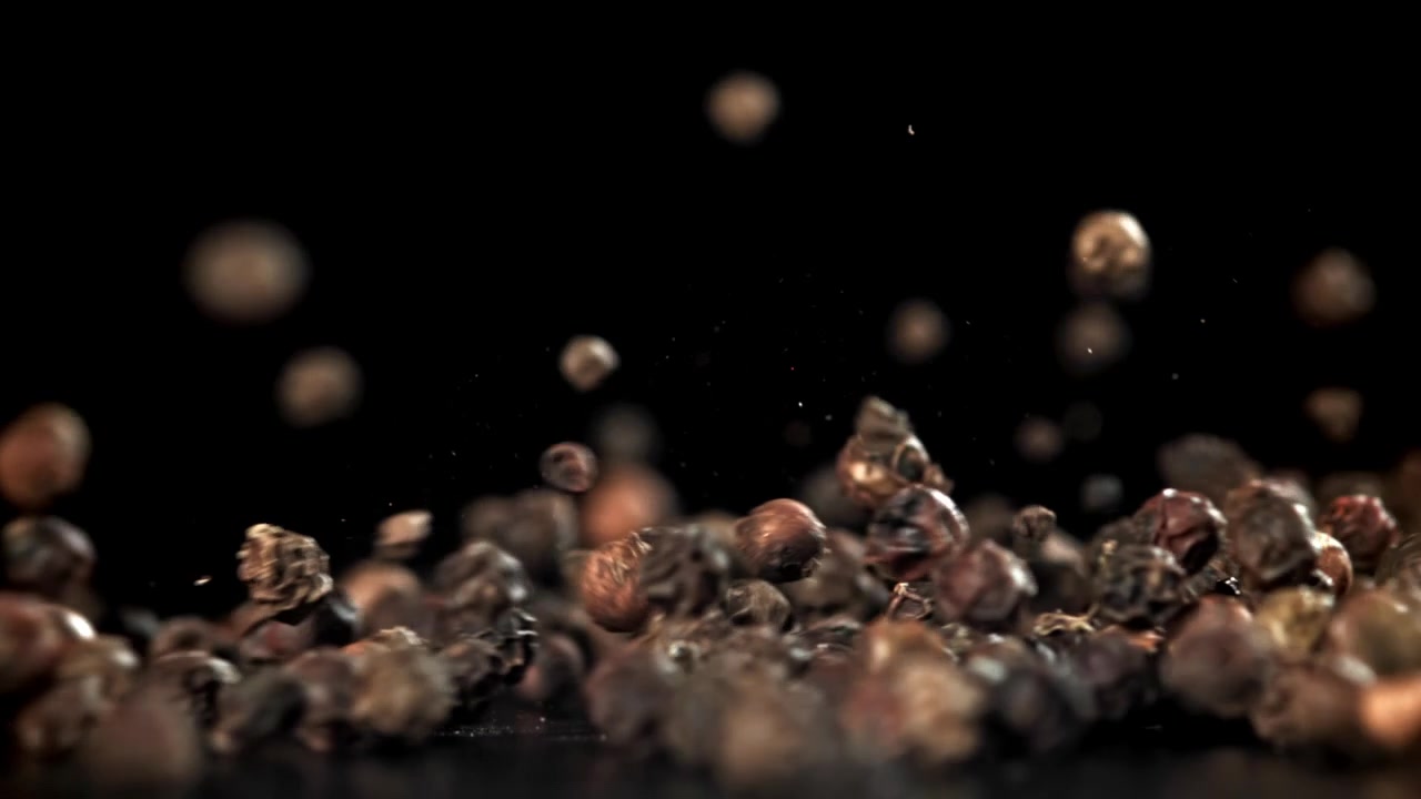 Black Peppercorns Falling and Bouncing on a Dark Surface in Slow Motion