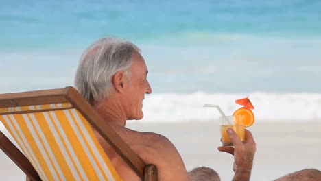 Hombre-Bebiendo-Un-Cóctel-Sentado-En-Una-Silla-De-Playa