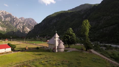 tranquilo pueblo alpino de theth en albania, iglesia tradicional y casas con fondo de montañas