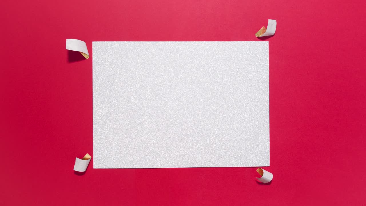 Stop motion silver glitter card is taped to a bright red background, party ready copy space