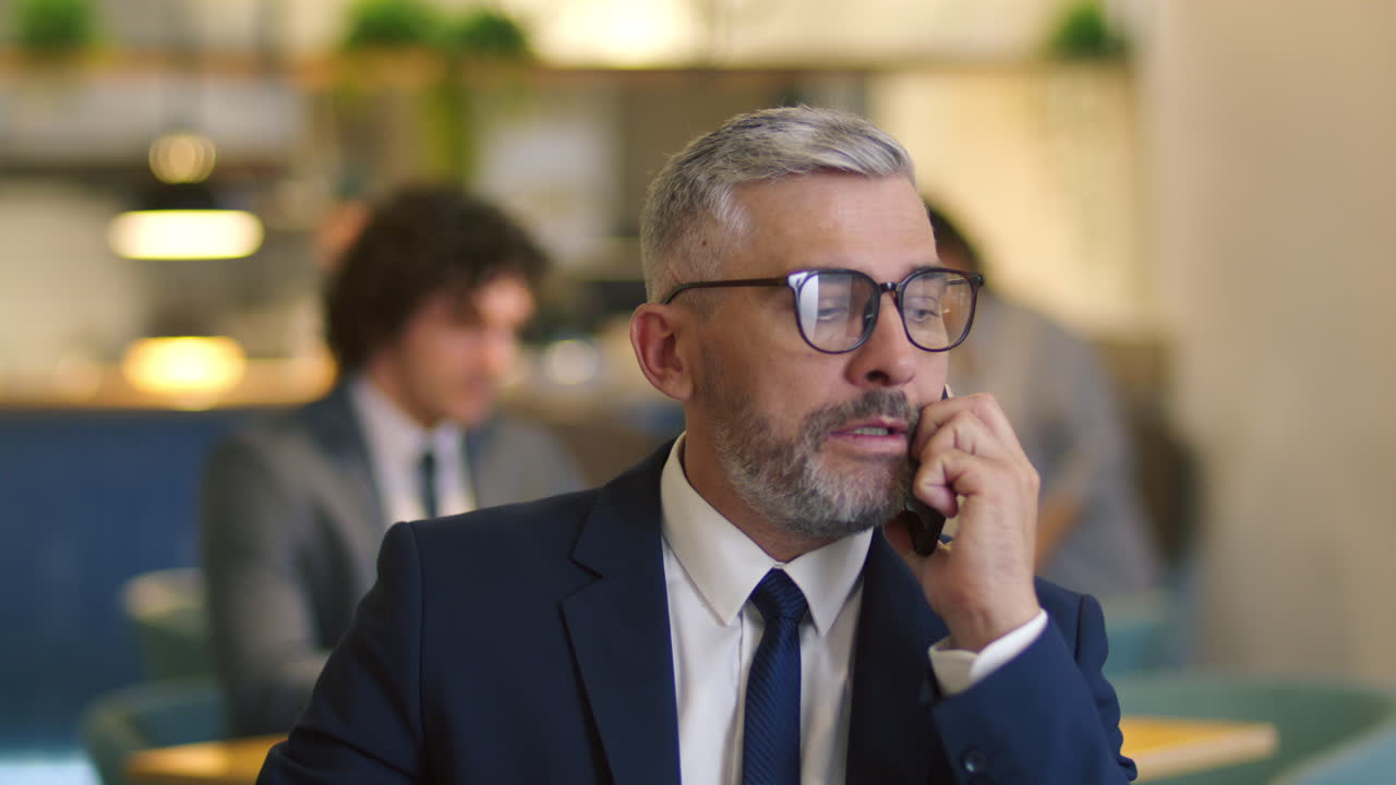 Uomo d'affari senior in abito formale che effettua una telefonata al ristorante