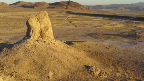 quick aerial pan around view of two of the trona pinnacles in the mojave desert during a bright yellow sunset