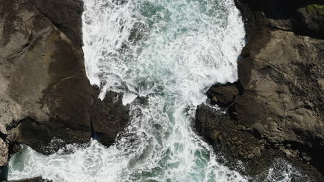 Agua-Blanca-Salpicando-Rocas-Después-De-Romper-En-Una-Cala-Estrecha