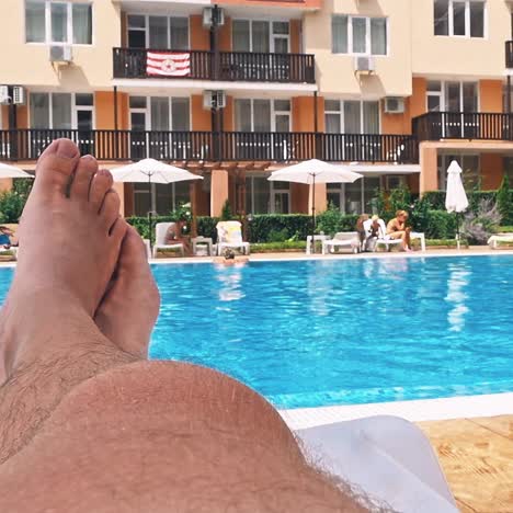 personas sentadas a la orilla de la piscina de un resort durante las vacaciones de verano