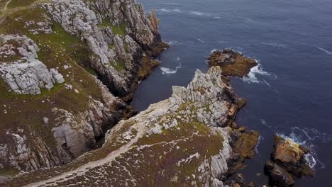 flying above a piece of land with a rocky cliffside by the sea