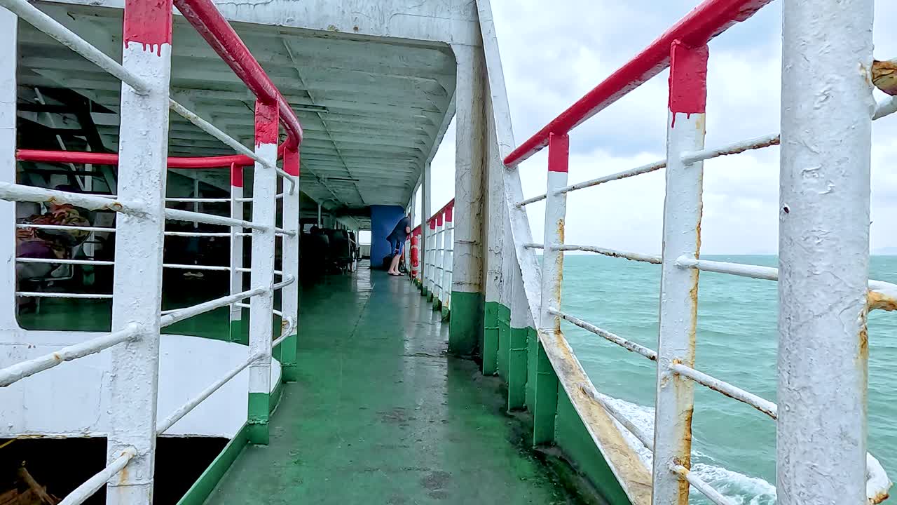 A tranquil ferry ride along Koh Samui's coast, showcasing vibrant railings and expansive ocean views under overcast skies