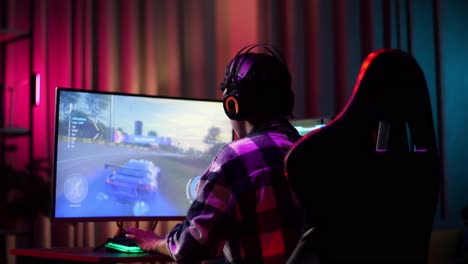 asian teen boy gamer wearing head phones and playing video game on computer, playing a racing video game