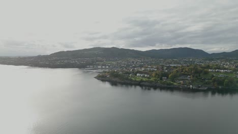 an aerial shot captures a coastal town surrounded by calm waters and mountains. the landscape creates a sense of peace and natural grandeur