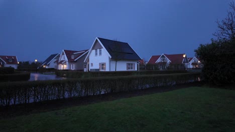 abendansicht eines ruhigen wohnviertels in der dämmerung, mit gut gepflegten häusern und nassen straßen nach dem jüngsten regen