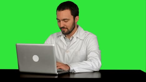 concentrado médico masculino usando portátil en la oficina médica en una pantalla verde, llave de croma