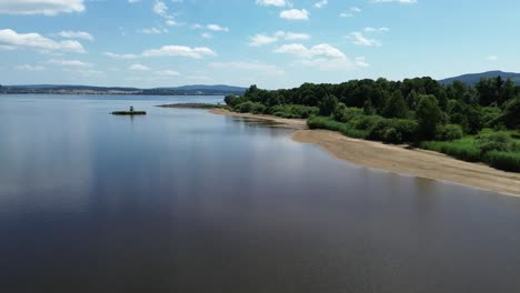 Filmischer-Blick-Von-Einer-Drohne,-Die-über-Einen-Sandstrand-Am-Ufer-Eines-Großen-Blauen-Sees-Fliegt