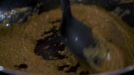 stir fry fresh brown massaman curry paste in a non stick black pan