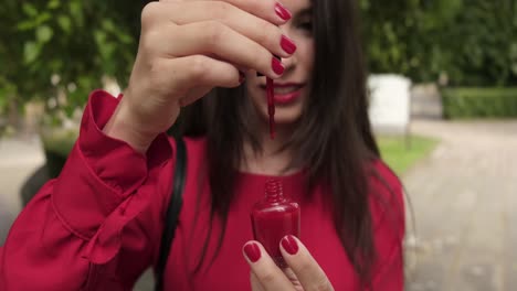 chica muy agradable abre esmalte de uñas rojo