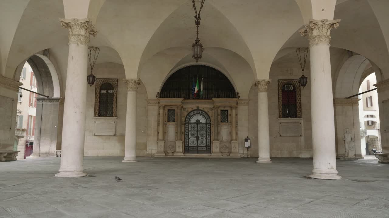 Vista di un grandioso ingresso con un cancello in ferro decorato sotto un porticato a volta con colonne corinzie e una lanterna sospesa a Brescia, Italia