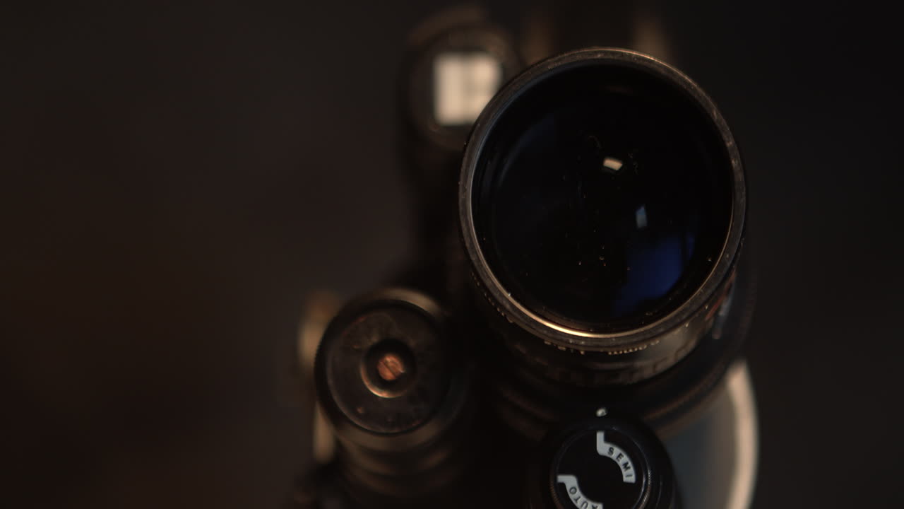 Lento zoom verso il barilotto scuro e retrò di un obiettivo da 16mm. Dettaglio di attrezzatura classica per il cinema, la produzione e temi multimediali di fotografia e videografia.