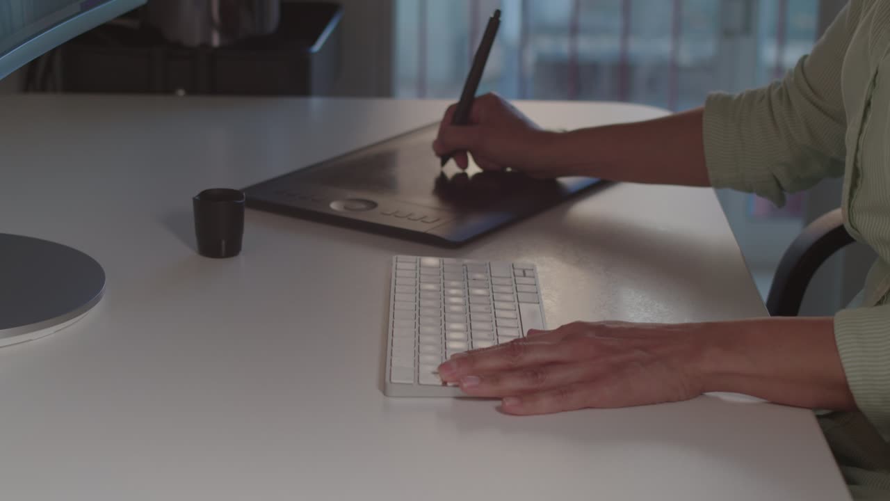 A close-up of a woman hands, using a digital pen and tablet at work.