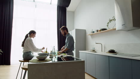 glückliches liebespaar, das in einer modernen küche einen leckeren salat zubereitet