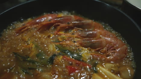 식당에서 일본 나베 전골에 새우, 두부, 야채를 끓이고 있습니다.