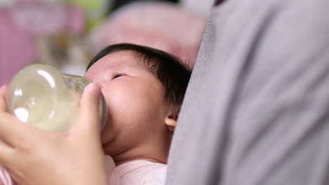 crying as it is waiting to be fed, a newborn child feeds on a formula milk in a feeding bottle held by her mother