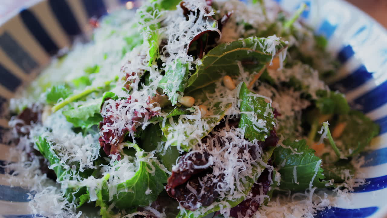Close up of a salad with leafy green and grated parmesan on top