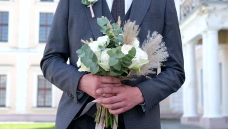close up of young stylish groom hands holding beautiful white wedding bouquet close up of young stylish groom hands holding beautiful white wedding bouquet