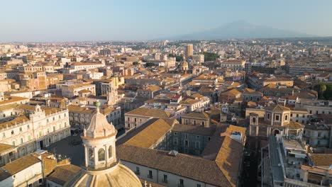 amazing aerial view of domed cathedral in catania, italy with famous mount etna volcano in background