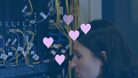 Animation-of-hearts-over-caucasian-businesswoman-in-server-room
