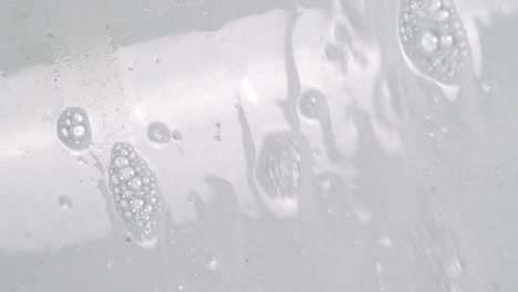 agua jabonosa que fluye hacia abajo en una pared blanca brillante