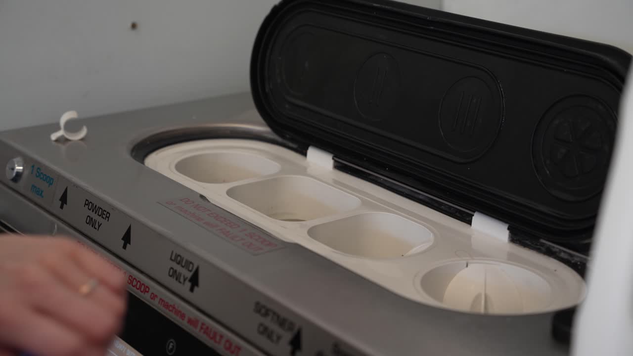 mano femenina vierte detergente líquido para la ropa en la parte superior de la lavadora en la lavandería