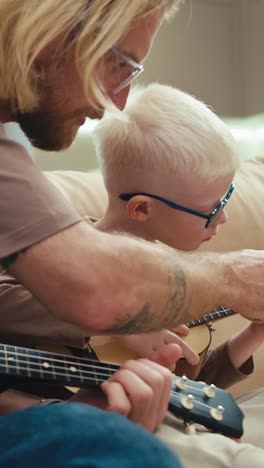 father and son learning ukulele together