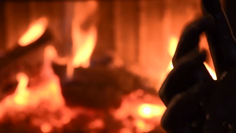 young female hand painted with black color moving smoothly with a blurred fireplace in the background