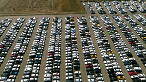 aerial footage of finished cars ready to be shipped on huge distribution center