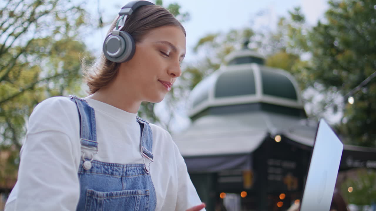 Earphones girl talking virtual conference looking laptop webcam outdoors closeup