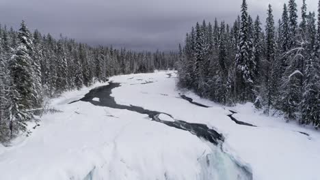 Stream-flowing-through-snowy-forest-during-winter-4k