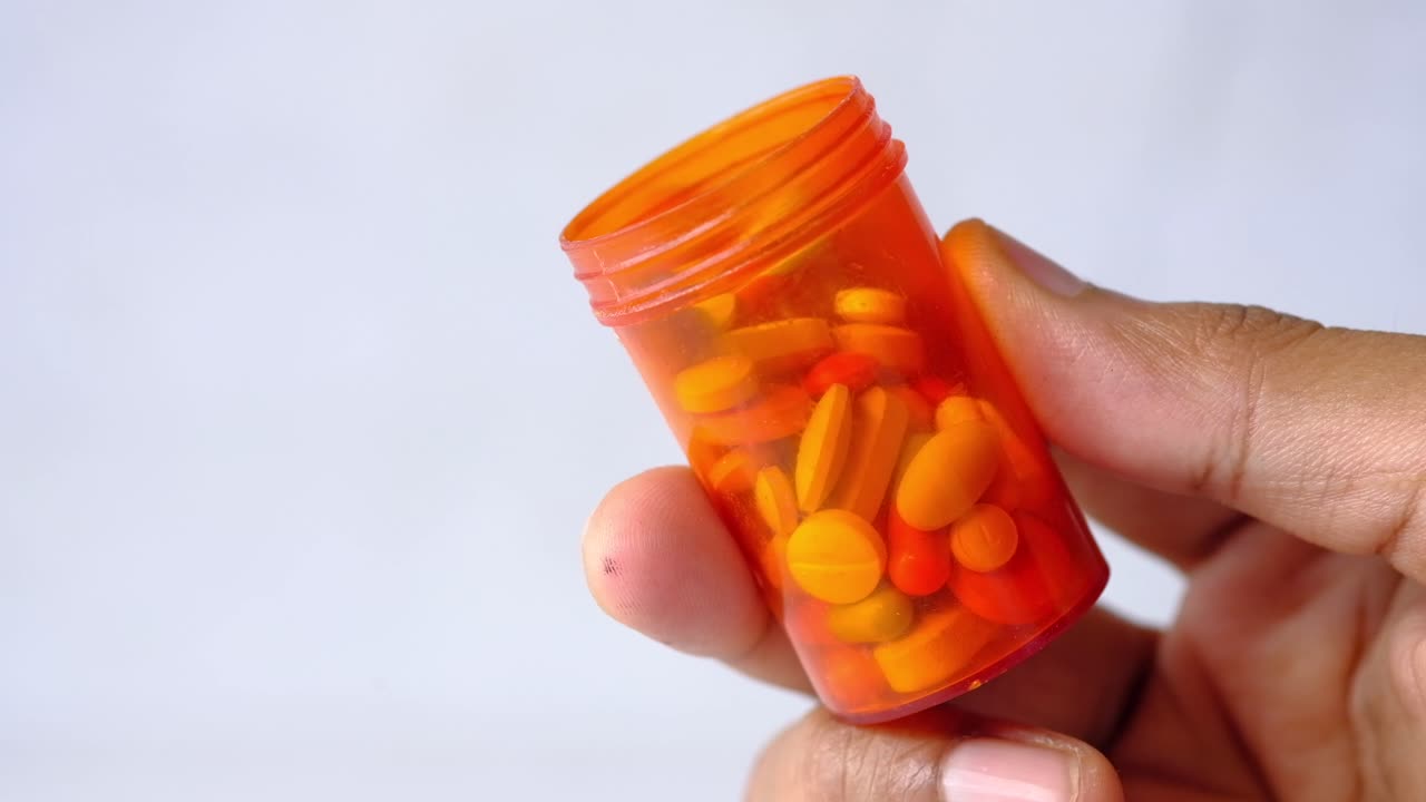 Orange pill bottle in hand