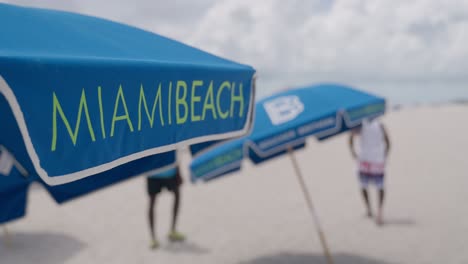 miami beach sign on beach umbrellas in slow motion shot