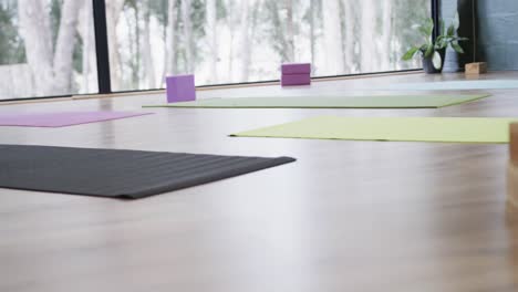 colorful yoga mats with cork blocks and singing bowl on floor in yoga studio