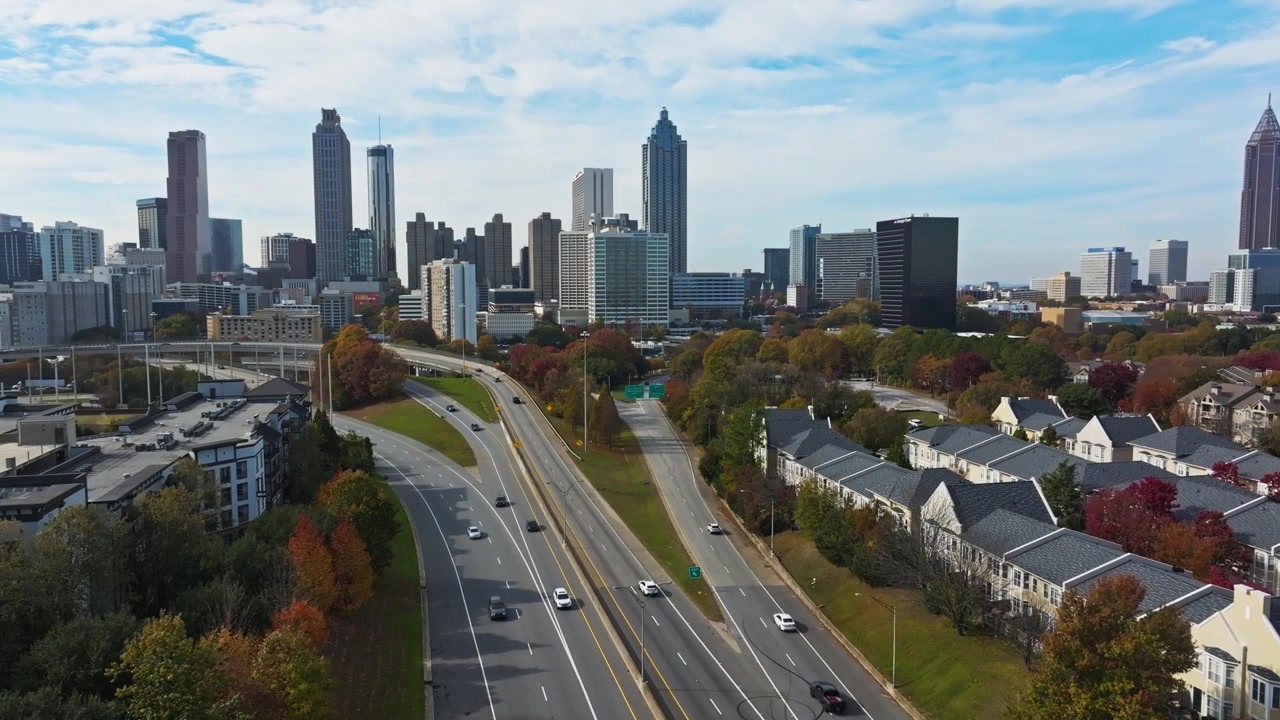Viale urbano con il famoso skyline del centro di Atlanta e i grattacieli, lussuose case a schiera in autunno sotto il cielo azzurro e limpido, Georgia. Ripresa con drone.