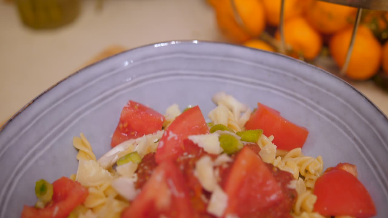 부엌에 있는 나무 테이블에 있는 보라색 그릇에 토마토, 파마산, 파를 넣은 파스타 식사를 만든 요리사의 전망