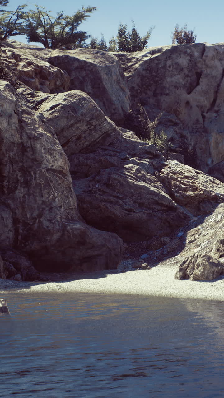 Grandi rocce e acqua calma vicino alla riva durante una giornata di sole splendente.