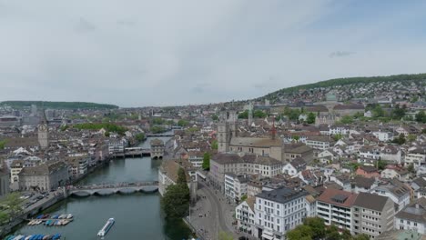 Toma-De-Drone-En-órbita-Alta-Que-Muestra-El-Horizonte-De-La-Ciudad-De-Zurich,-El-Horizonte,-Los-Puentes,-El-Río-Y-La-Catedral.