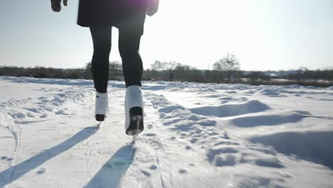 woman is sliding along frozen ice on river. female feet in white skates are skating on frozen lake. female skater is skating outdoor. winter sport activities